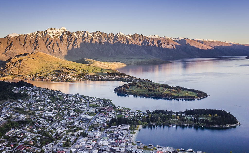 Golden sun cloaks The Remarkables’ dramatic mountain peaks as the day draws to a close in Queenstown, New Zealand